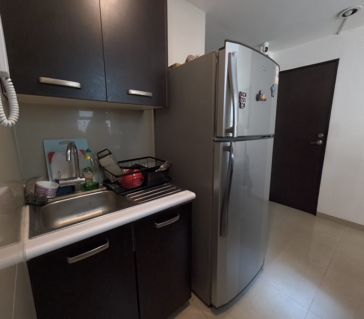 Cocina con refrigerador y gabinetes oscuros