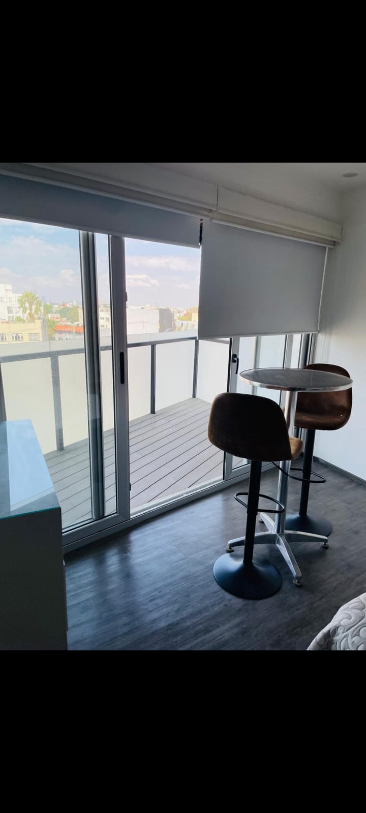 Balcón con sillas tipo bar y vista a la ciudad