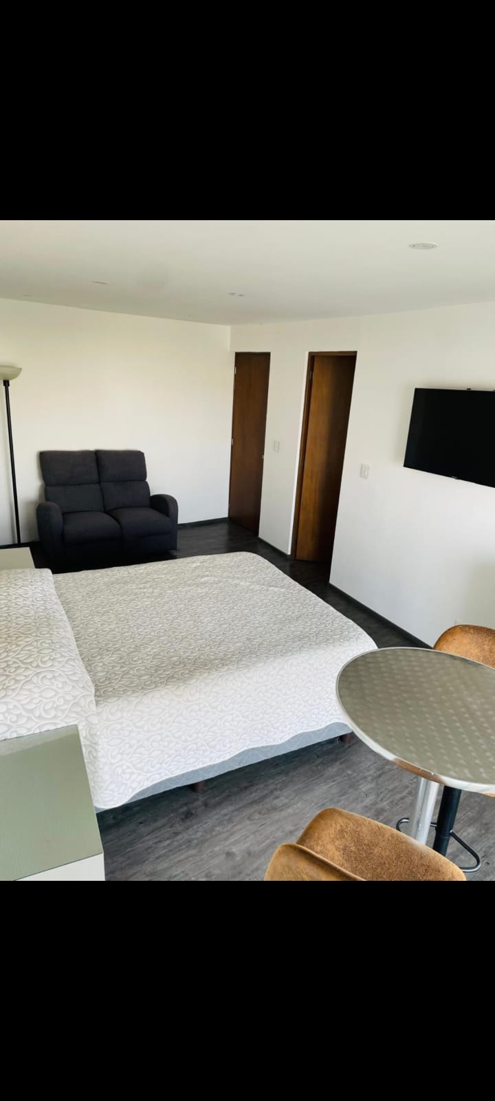 Habitación con sillón negro y acceso al balcón